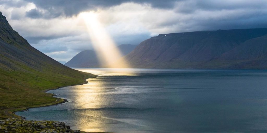 Ray of Sunlight breaking through clouds over ocean bay