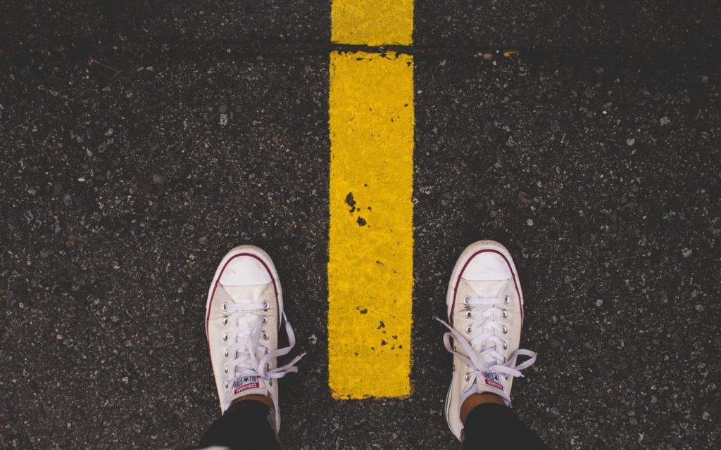 Person straddling two sides of a highway divider line