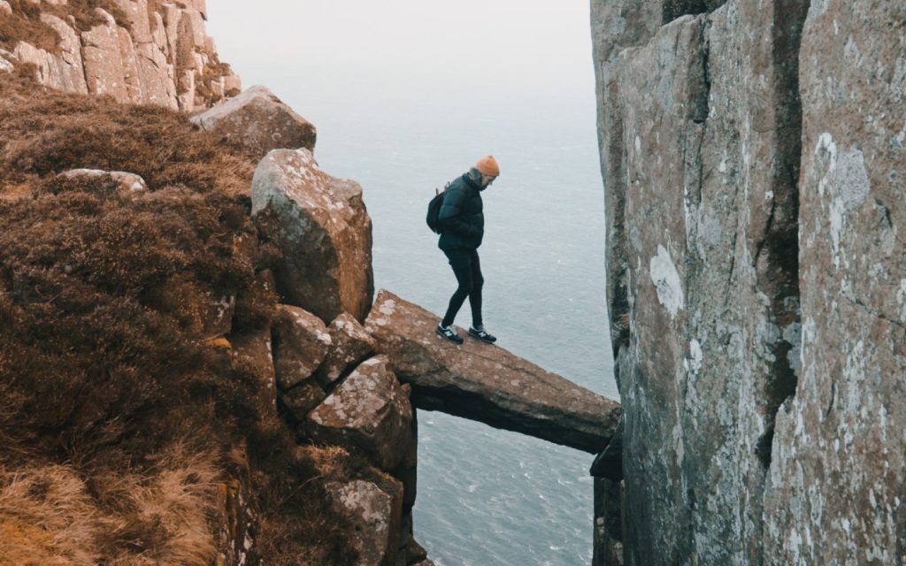 Climber crossing precarious rock bridge