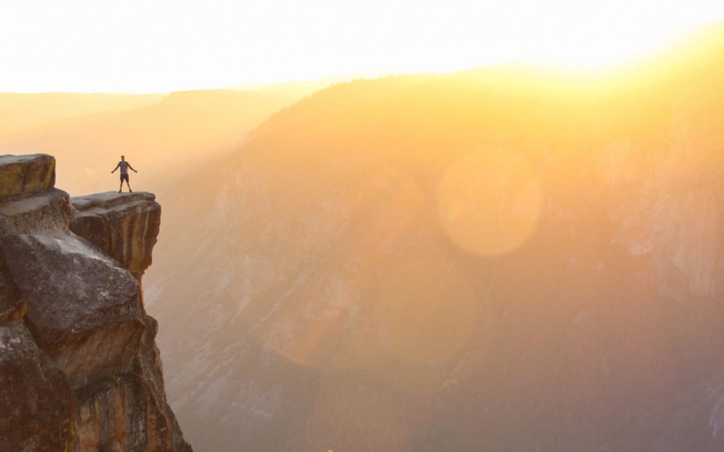 Man standing on edge of cliff in the sunlight