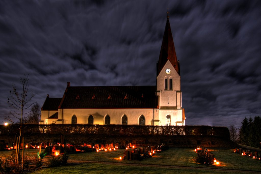An image of a cemetery outside a church on the feast of All Hallows